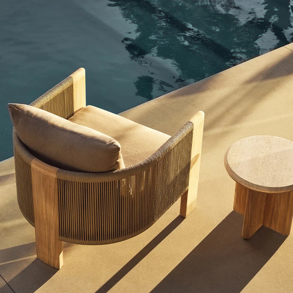 Harbour Outdoor teak lounge chair with a woven back beside a pool
