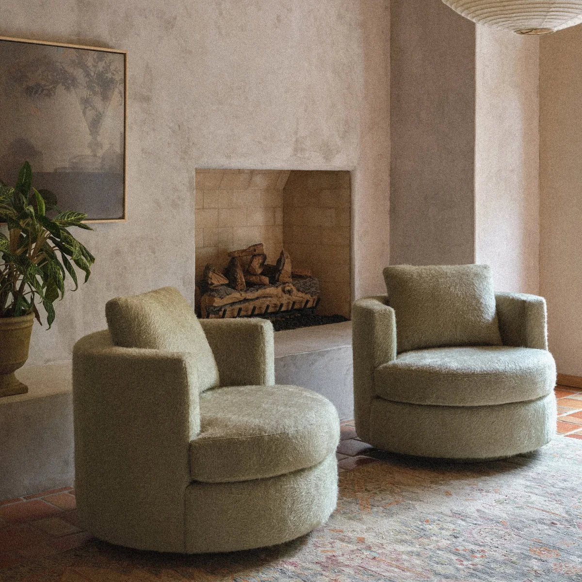Two American Leather Emma swivel chairs in sage fabric in front of a stone fireplace