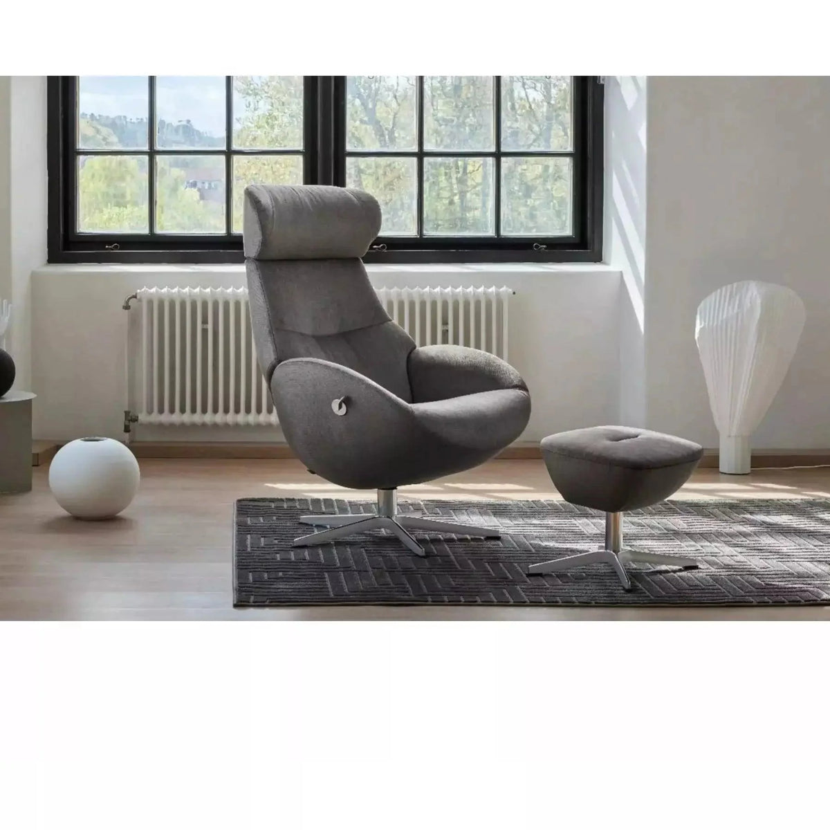 Conform Globe swivel recliner and matching ottoman in dark leather beside a tall window in a bright, white room