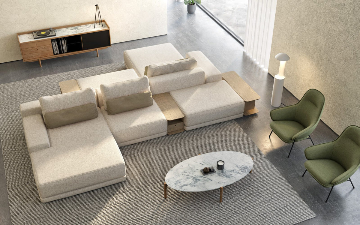 Huppé Milton modular sofa in cream with built-in wood tables, an oval marble coffee table and two green lounge chairs