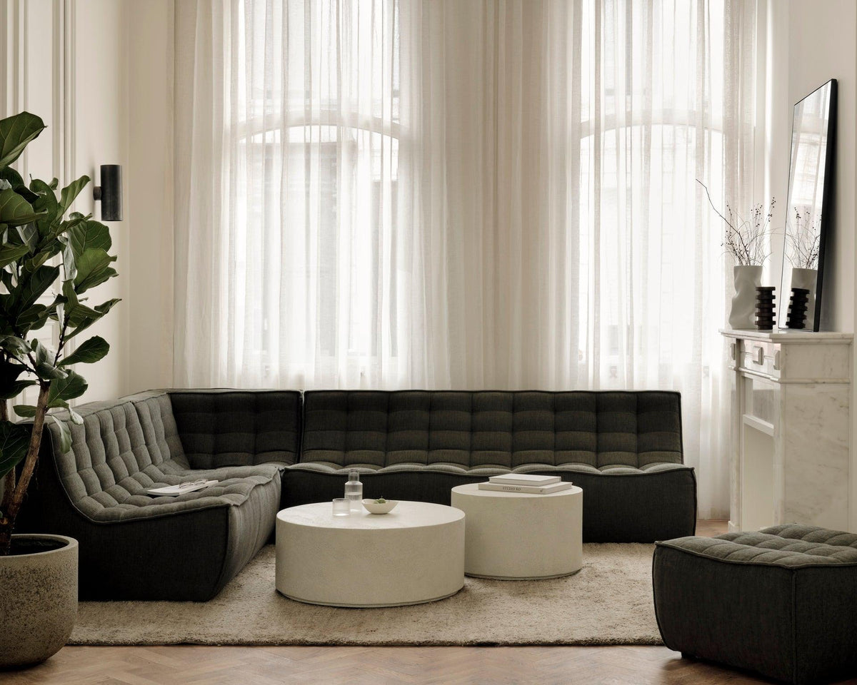 Ethnicraft N701 modular sectional in moss green fabric with round white coffee tables in a bright living room