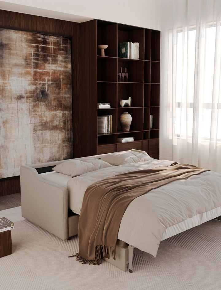 Carnell sleeper sofa opened into a bed with bedding beside tall bookshelves