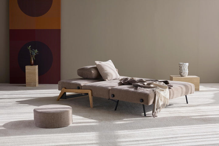 Cubed sleeper sofa with oak legs reclined into lounge position with pillows
