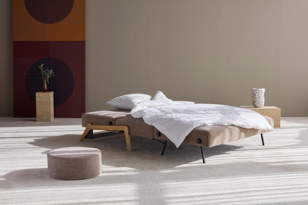 Cubed sleeper sofa with oak legs opened into a bed with white bedding