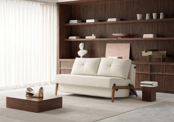 Cream Cubed sleeper sofa with dark wood legs reclined with pillows