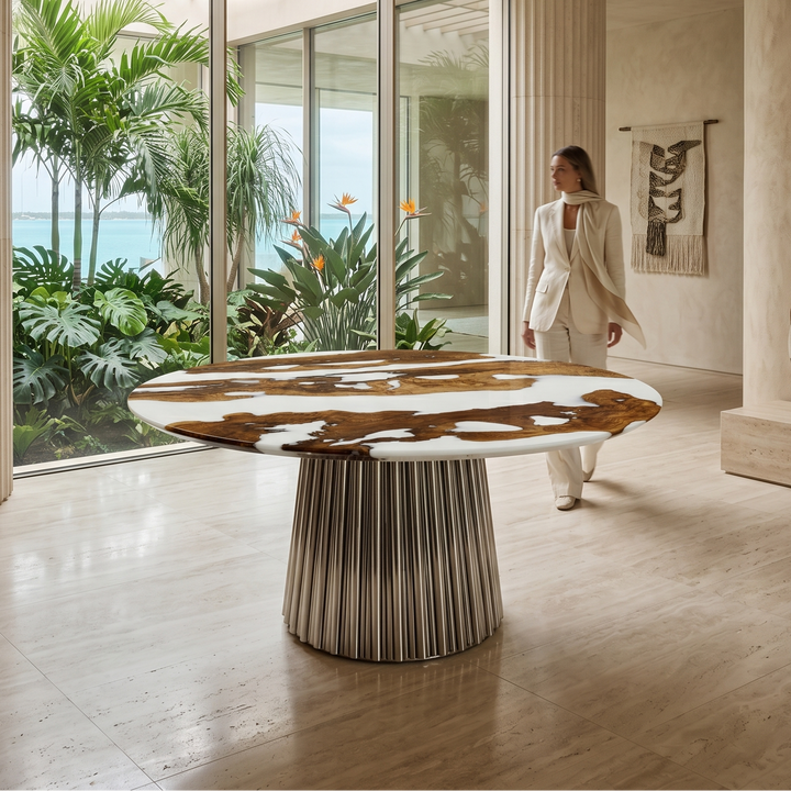 Arditi Chrome Grazia olive wood and white resin dining table in a bright garden-facing interior with a woman beside its polished chrome pedestal base