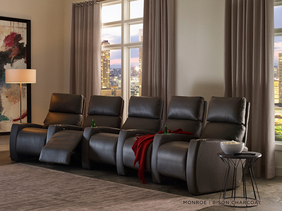 American Leather Monroe charcoal theater seats in a city-view media room, with one seat reclined