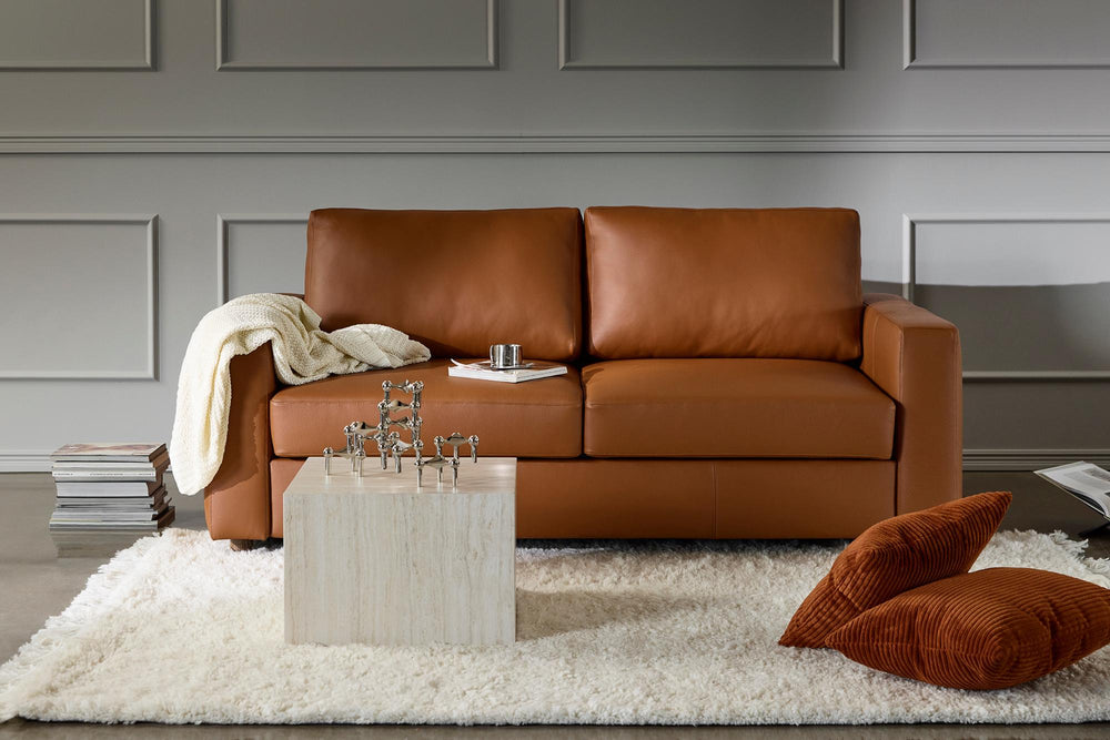 Cognac leather Neah queen sleeper sofa on a white shag rug with pillows