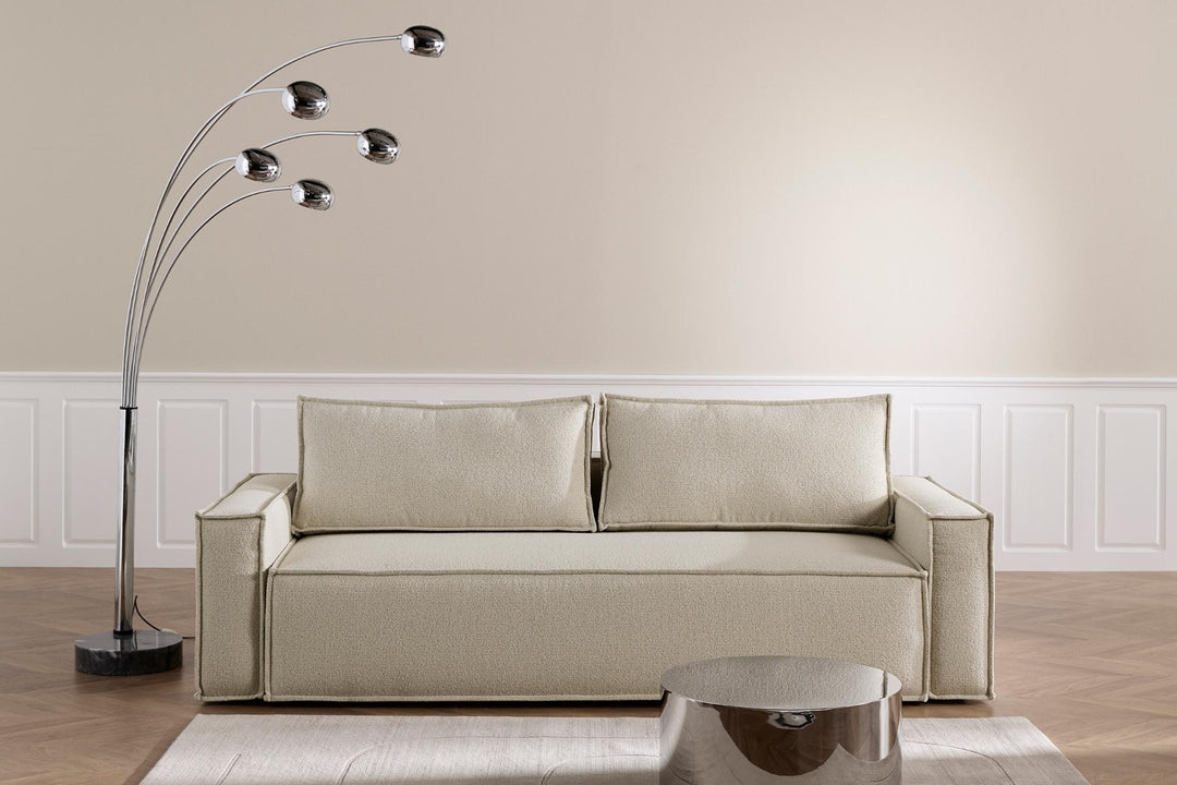 Cream Newilla sleeper sofa below a multi-arm floor lamp in a white paneled room