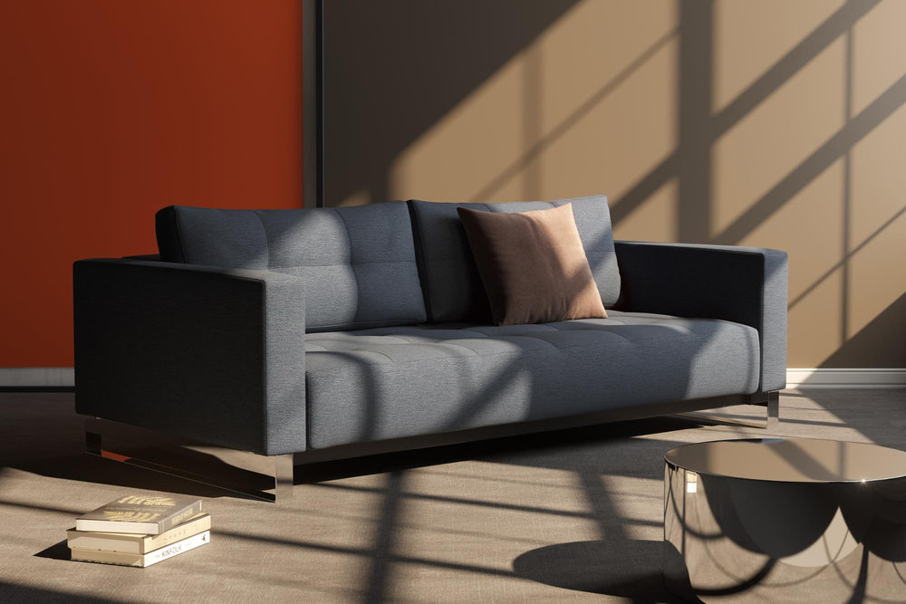 Charcoal Cassius D.E.L. sleeper sofa with chrome legs in sunlight against an orange wall
