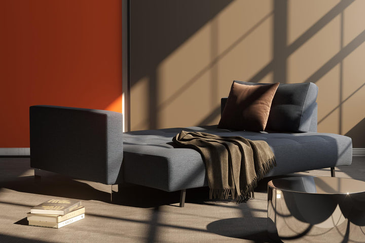 Charcoal Cassius D.E.L. sleeper sofa with a throw in sunlight and shadow
