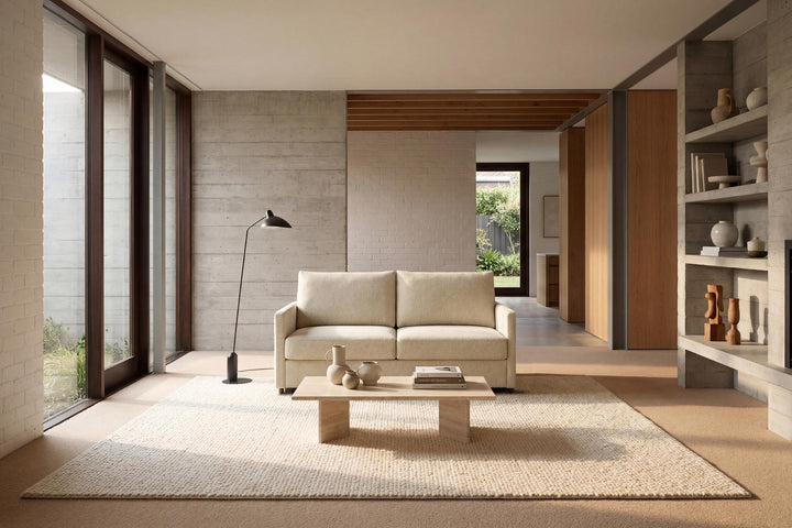Cream Neah sleeper sofa with slim arms in a long room with tall windows
