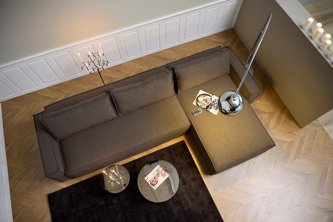 Overhead view of a dark gray Newilla sleeper chaise sectional on herringbone floor with arc lamp