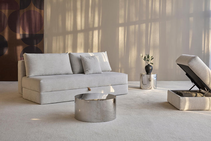 Cornila ottoman with its storage lid open beside a light gray Osvald sleeper sofa