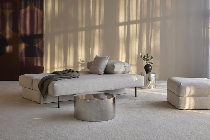 Light gray Osvald sleeper sofa reclined flat with pillows in a sunlit room