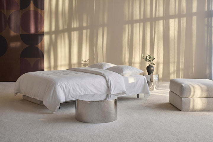Osvald sleeper sofa opened into a bed with white bedding in a sunlit room