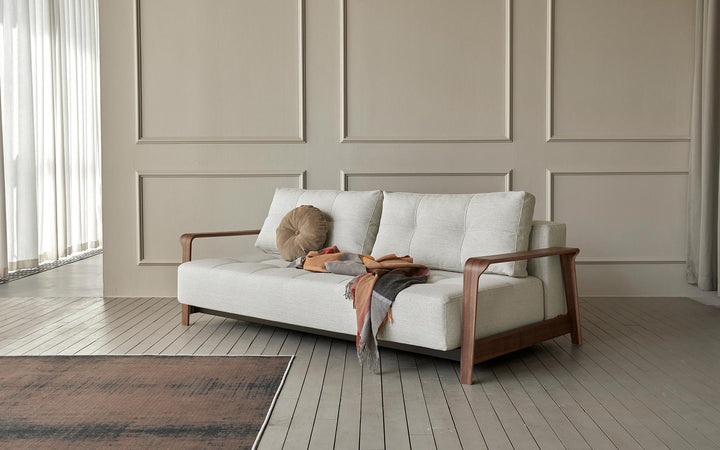 Ran D.E.L sofa bed in light fabric with bent wood arms in a paneled living room