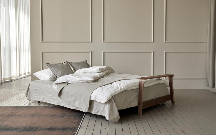 Ran D.E.L sofa bed opened into a queen bed with throw and pillows in a paneled room