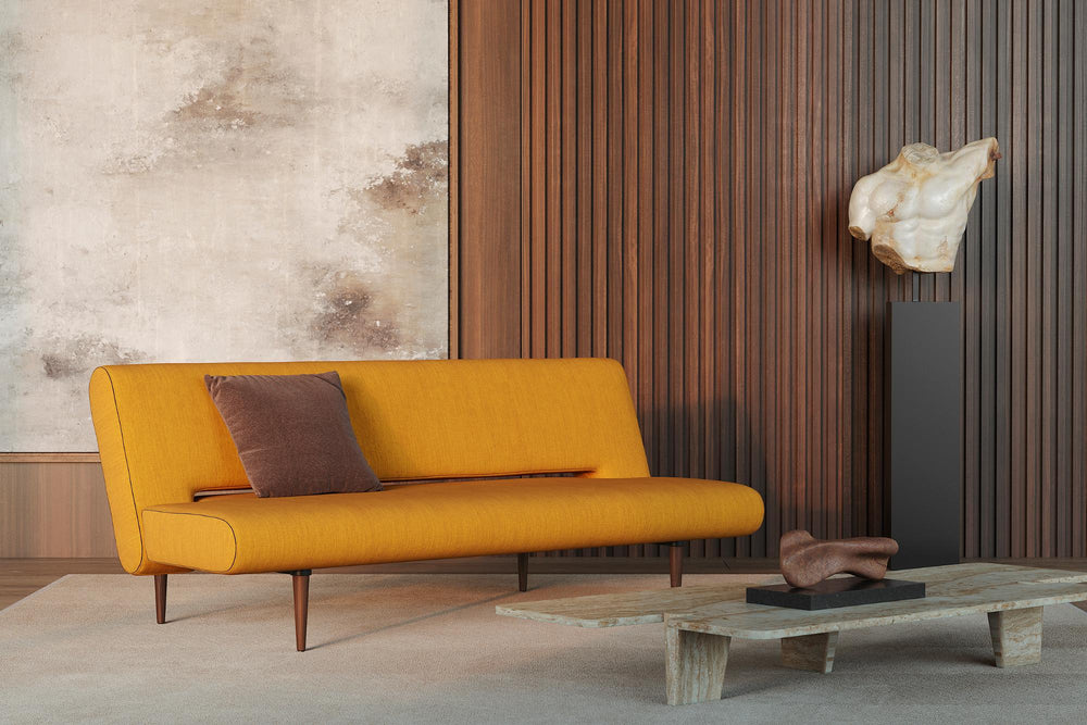 Mustard yellow Unfurl sleeper sofa against a wood slat wall with a low coffee table