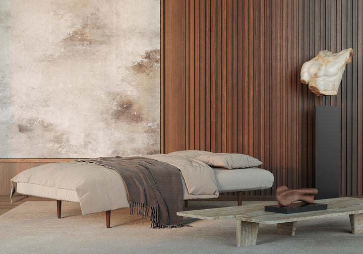 Unfurl sleeper sofa opened into a bed with gray bedding beside a wood slat wall