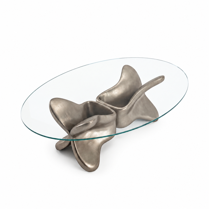 Arditi Psyche coffee table with clear oval glass top and satin chrome sculptural base on a white background, studio view