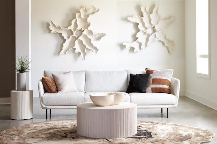 Phillips Collection Groovy White Stone coffee table in front of a white sofa with sculptural wall accents
