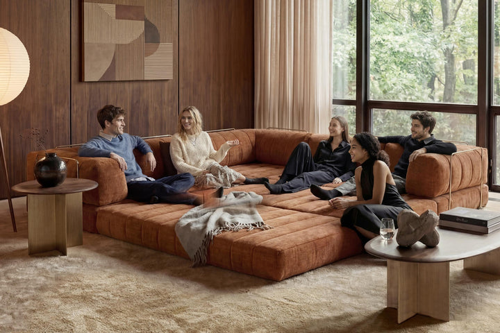 CozyPad Sleeper Sofa Corner with arms by Innovation Living in rust orange velvet with four friends lounging in a wood-panelled room