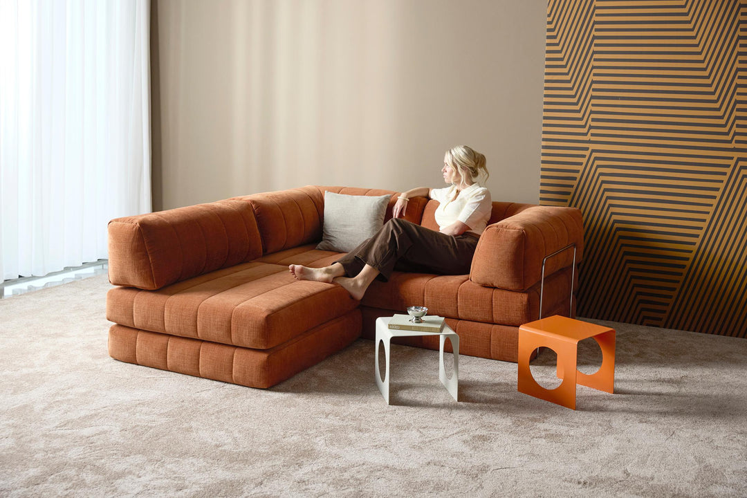 CozyPad Chair by Innovation Living in rust orange velvet with a woman relaxing beside white and orange side tables
