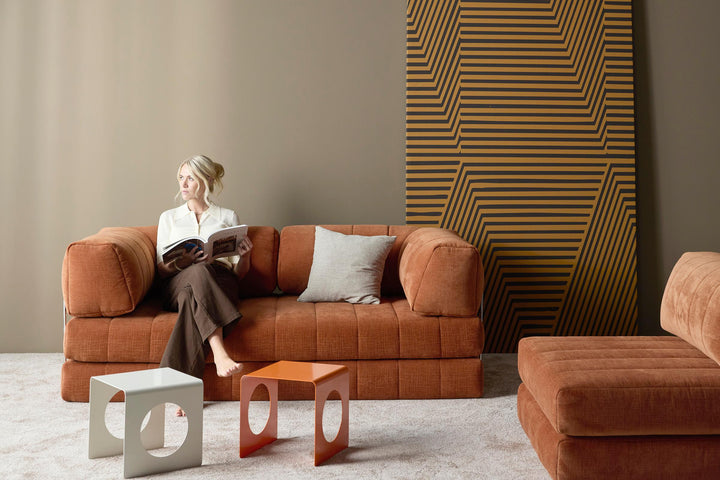 CozyPad Chair by Innovation Living in rust orange velvet with a woman reading on the pads beside an orange side table