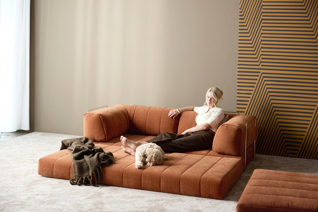 CozyPad Sleeper Sofa with arms by Innovation Living in rust orange velvet with a woman reading and a dog beside a striped wood wall