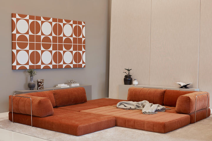 CozyPad Sleeper Sofa L-Shape with arm by Innovation Living in rust orange velvet opened wide as a lounge with a throw beneath a geometric wall print