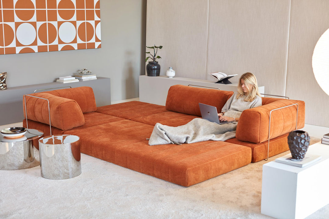 CozyPad Sleeper Sofa Grand with arms by Innovation Living in rust orange velvet opened into a lounge with a woman working on a laptop