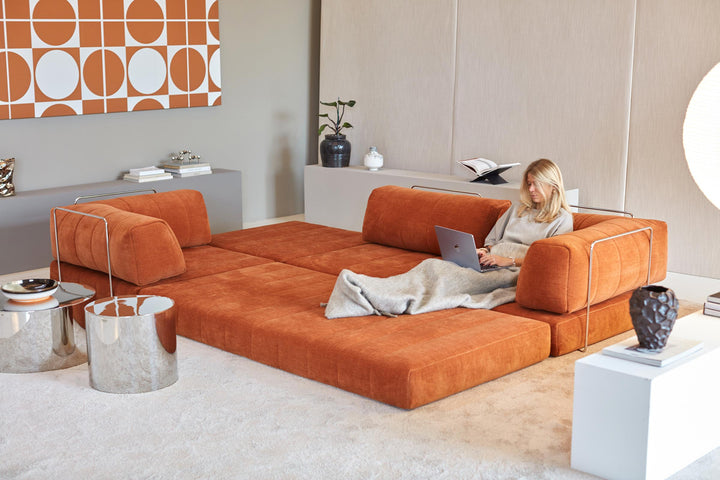 CozyPad Sleeper Sofa Grand with arms by Innovation Living in rust orange velvet opened into a lounge with a woman working on a laptop