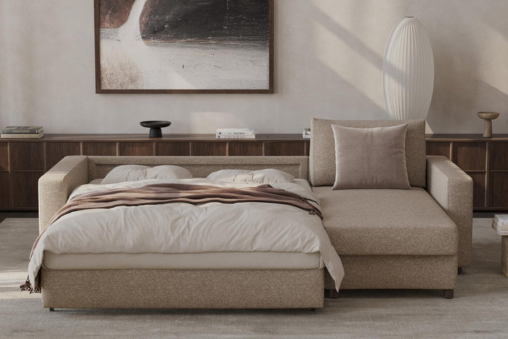 Neah Sleeper Chaise Sectional by Innovation Living opened into a bed with beige bedding in a bright room