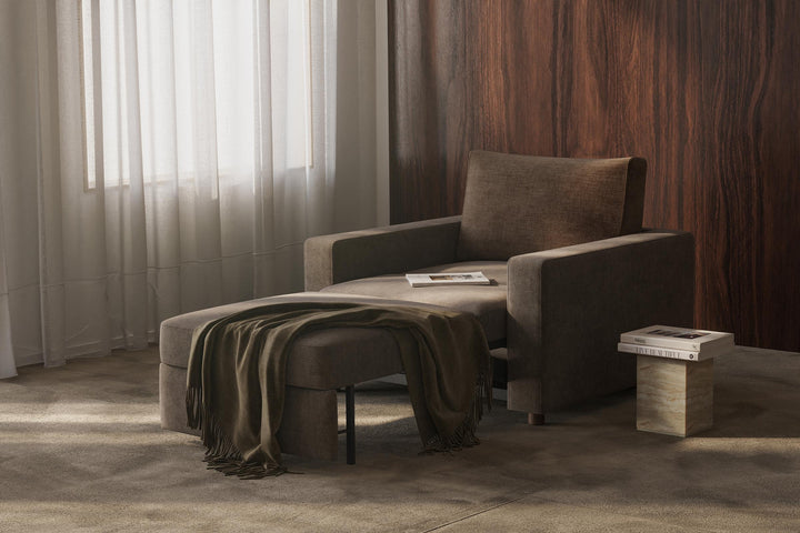 Neah Sleeper Chair by Innovation Living in dark grey with a throw on the extended seat and a side table