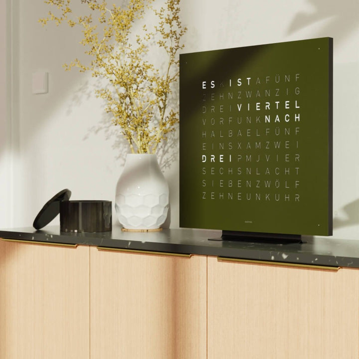 QLOCKTWO EARTH 45 Olive word clock above a wood sideboard