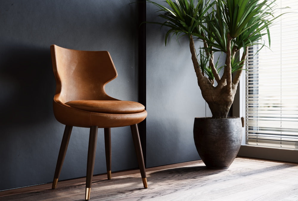 Brown upholstered dining chair beside a plant and window
