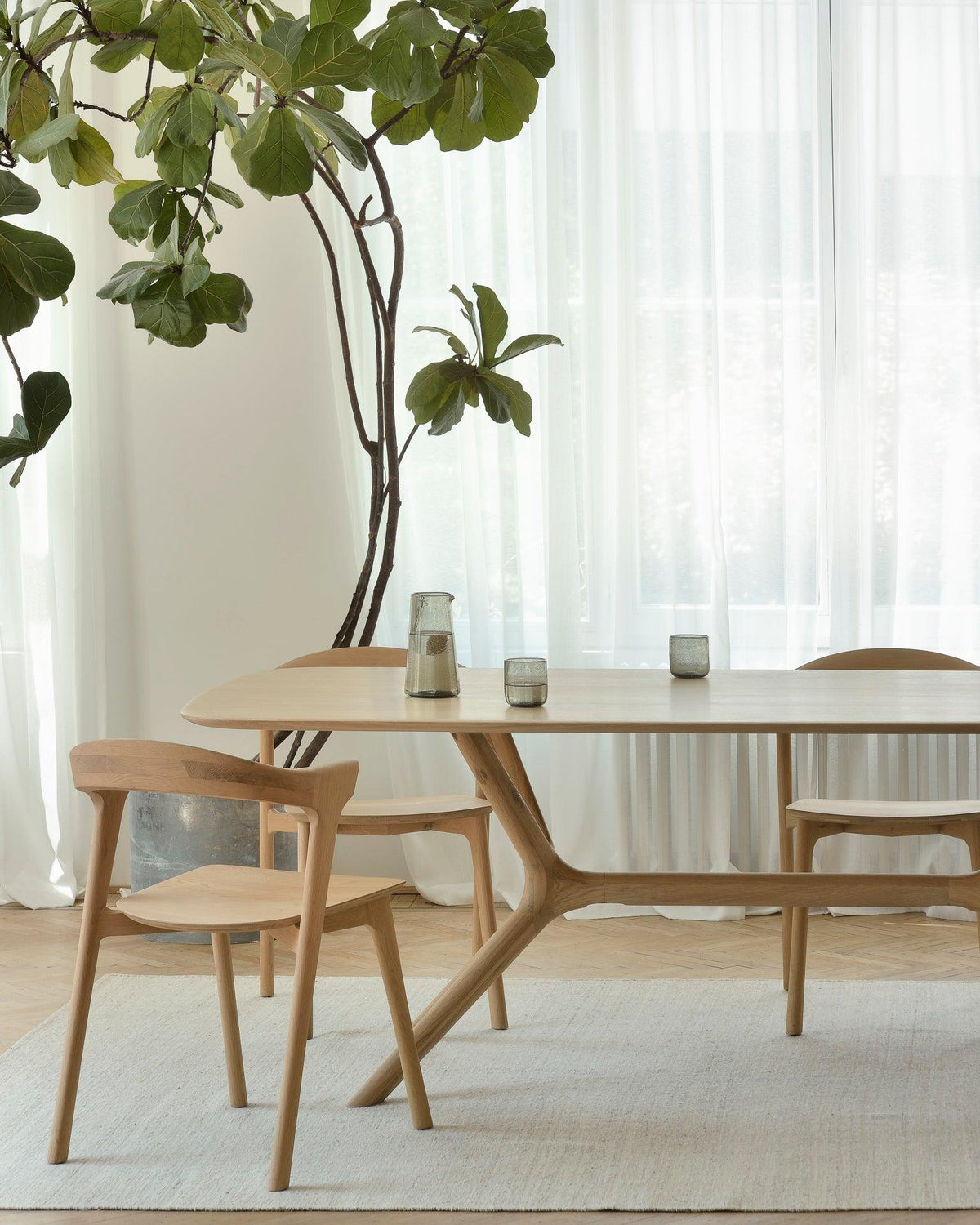 Ethnicraft wood dining table and chairs beside a bright window